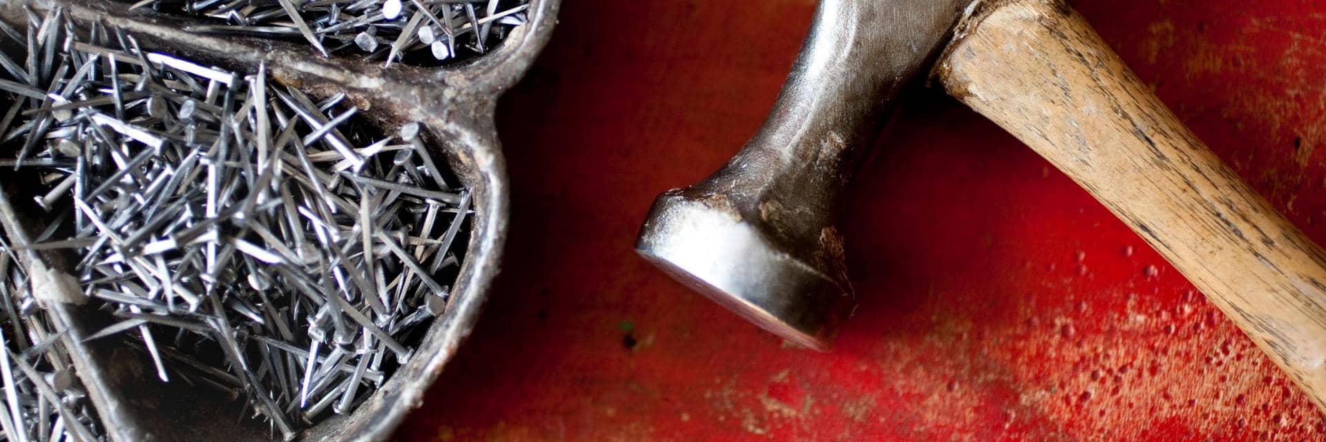  Hammer and nails on a red table.