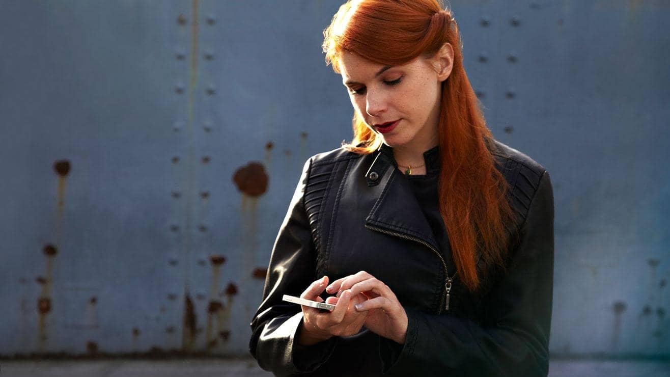 A woman wearing a leather jacket looking at her phone
