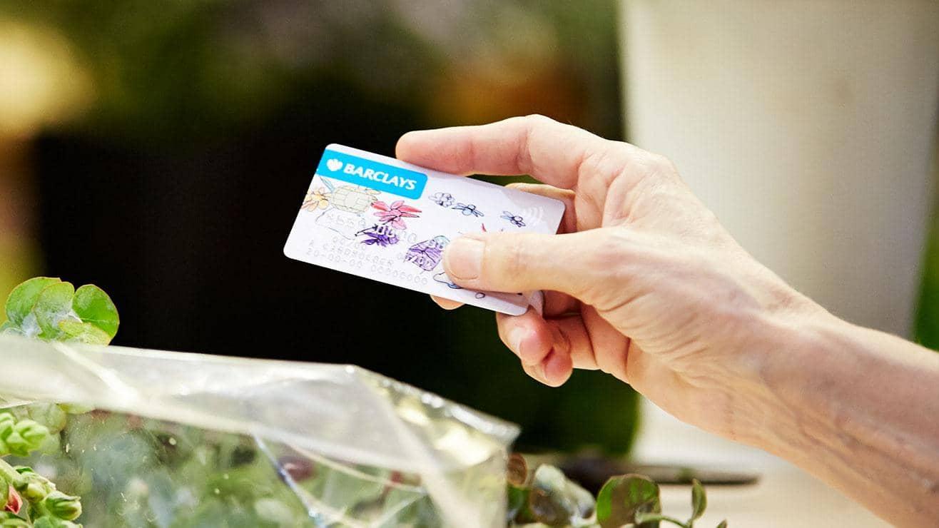 A hand holding a Barclays debit card