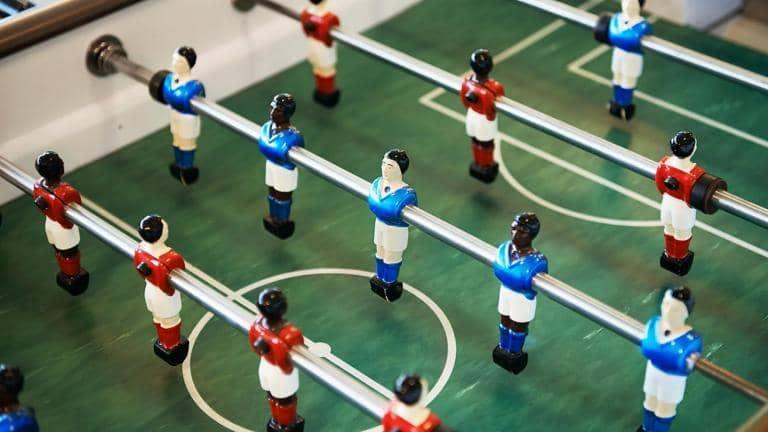 Close up of foosball table with players in blue shirts and red shirts