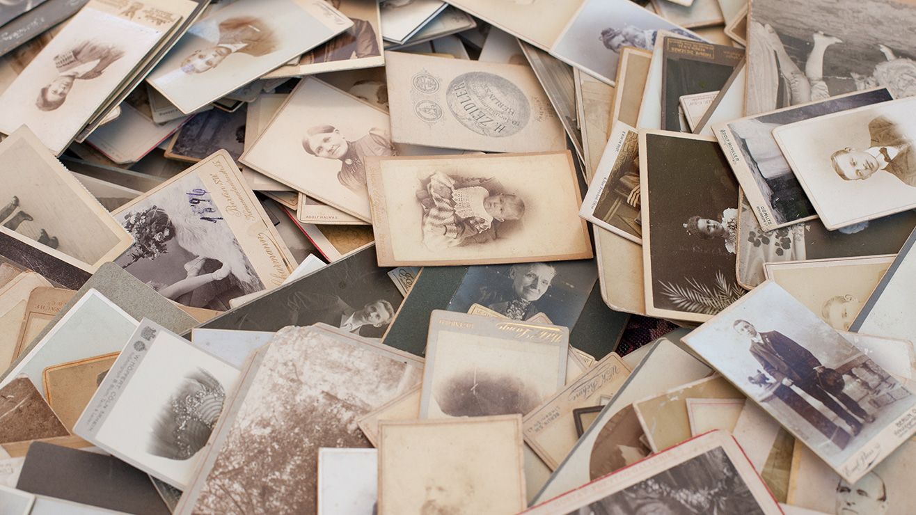 A pile of old black and white photographs, mostly portraits
