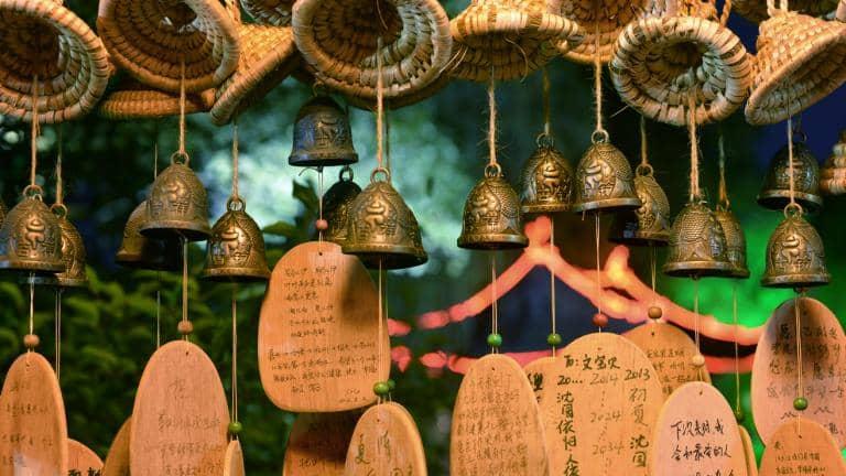 Small bronze wishing bells and pieces of wood inscribed with messages in Chinese hanging from string