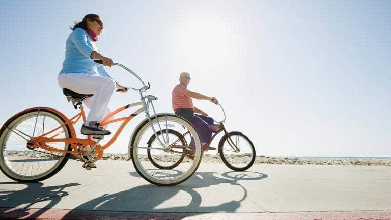  A man and a woman riding bikes along a coastal path

