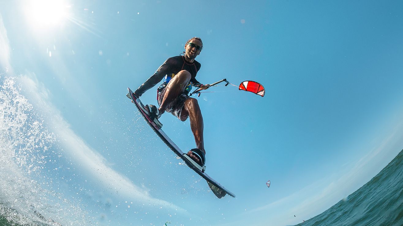 An action shot of a man in mid-air kitesurfing on the ocean
