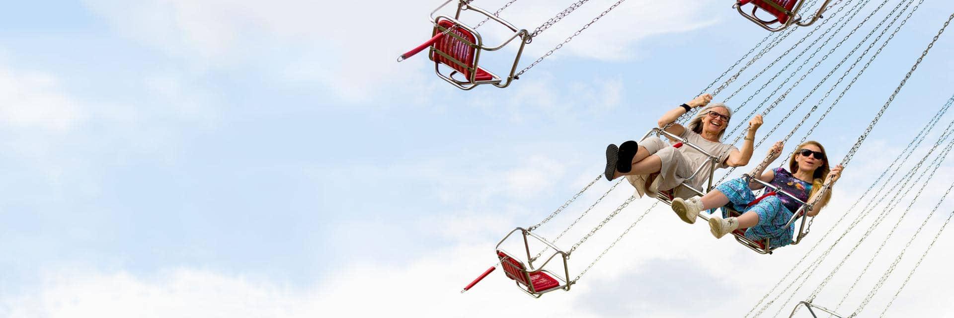 Two women in the air on a fairground swing ride
