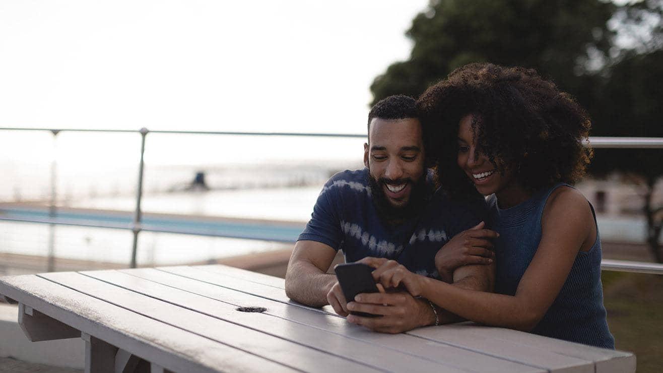 Couple look at a smartphone at a bench